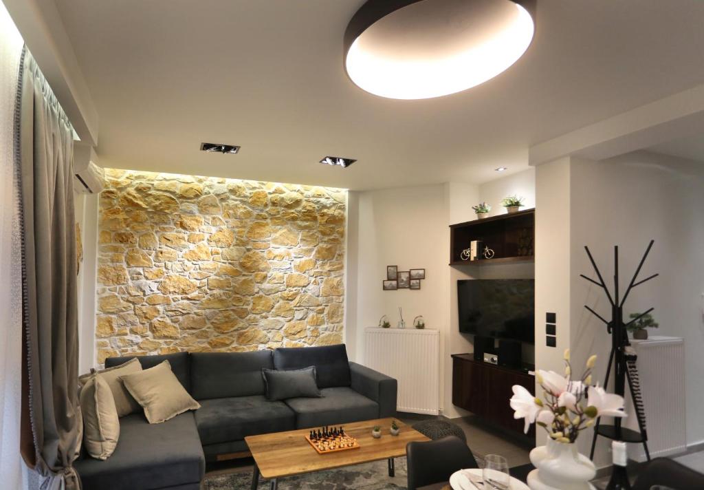 uma sala de estar com um sofá e uma parede de pedra em LA Larissa Luxury Apartments Koronis em Larisa