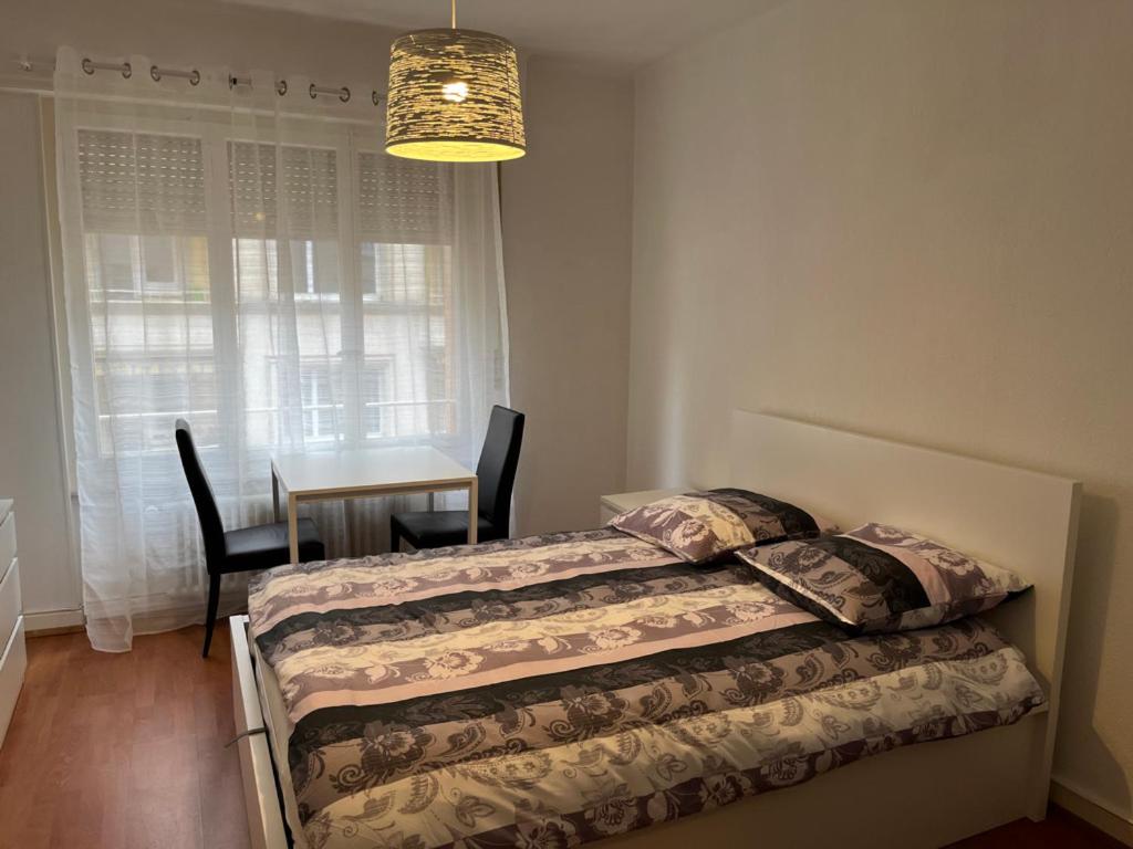 1 dormitorio con 2 camas, mesa y lámpara de araña en Gare-20-1, en Lausana