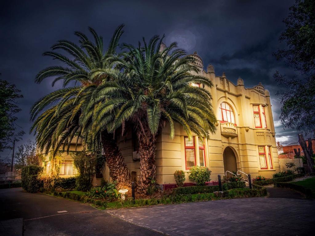 a building with a palm tree in front of it at Toorak Manor Hotel in Melbourne