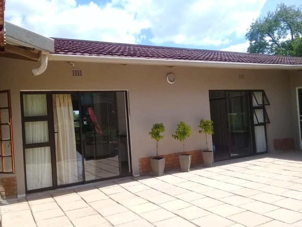 a house with sliding glass doors and potted plants at Genie's Nest Ooie 2 in Pretoria