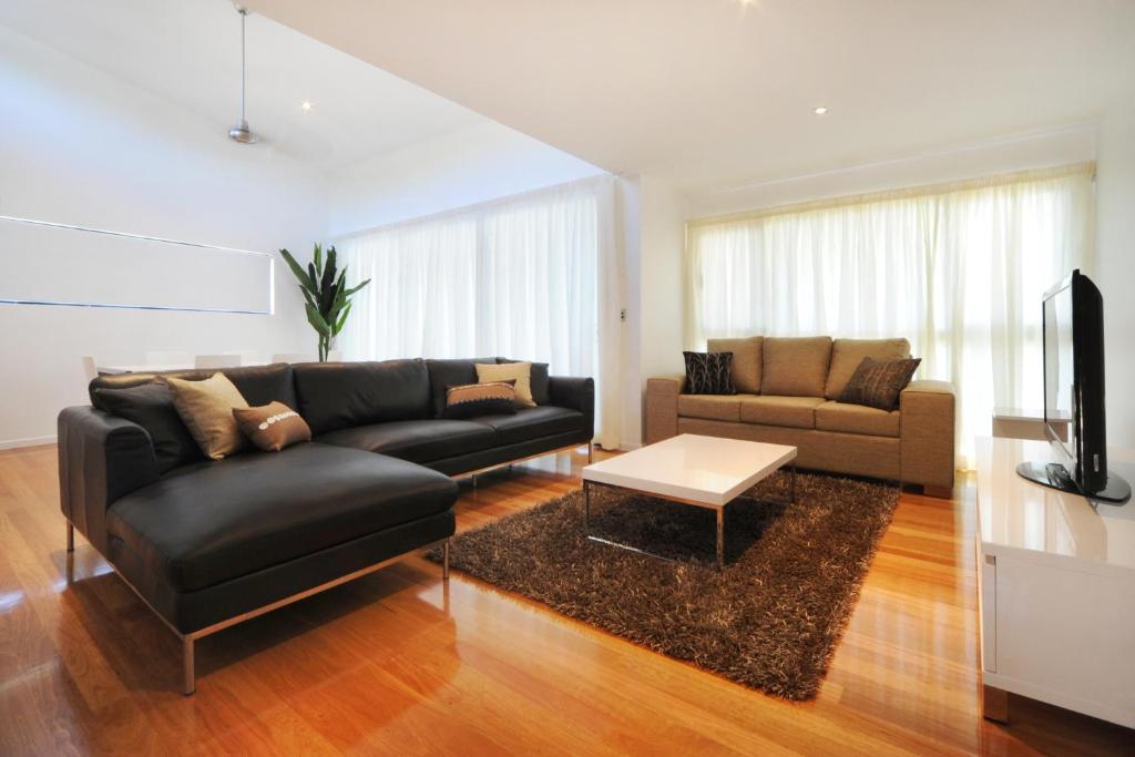 a living room with a black leather couch and a table at Pinnacle Apartments in Hamilton Island