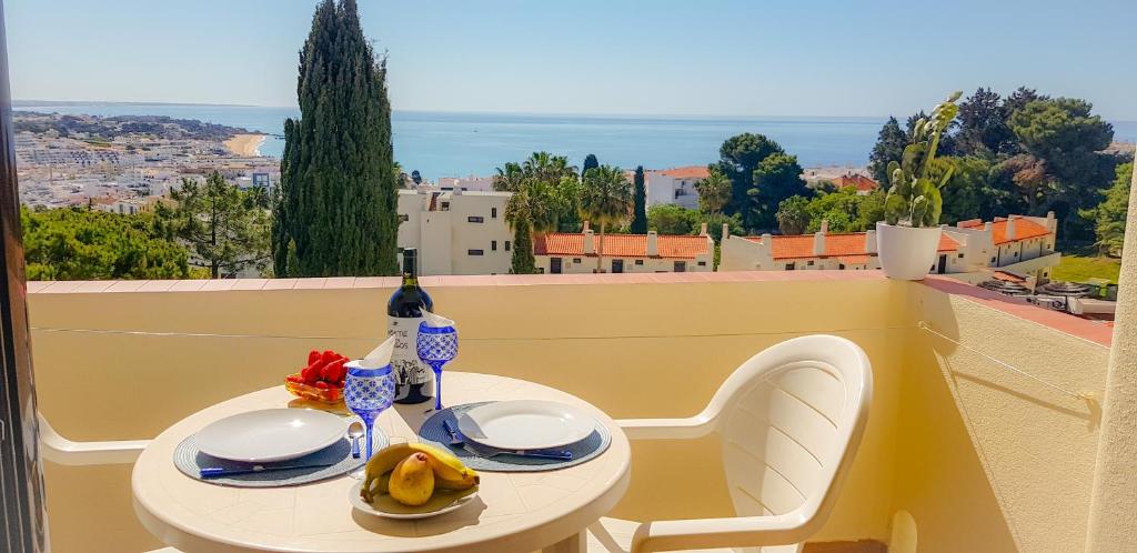 a table with plates and a bottle of wine on a balcony at Ocean View - Fantástico Studio em Albufeira in Albufeira