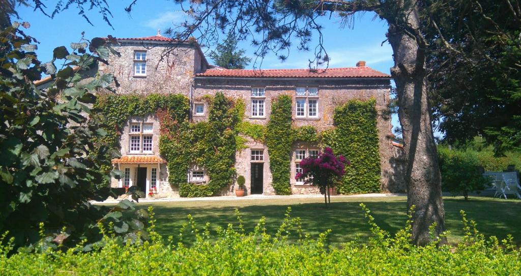 Une grande maison en briques recouverte de lierre dans l'établissement Gîte Mathurine, à Le Boupère