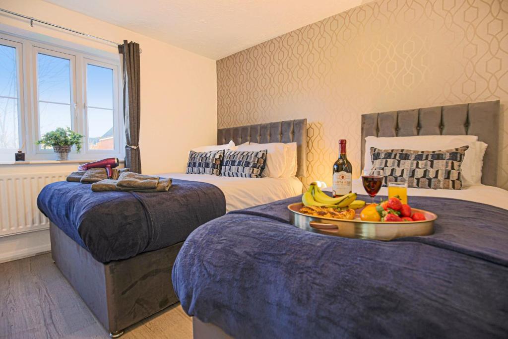 een hotelkamer met 2 bedden en een dienblad met fruit bij COSY 3 BED HOUSE to BICESTER OUTLET for BIG GROUP by Platinum Key Properties in Bicester