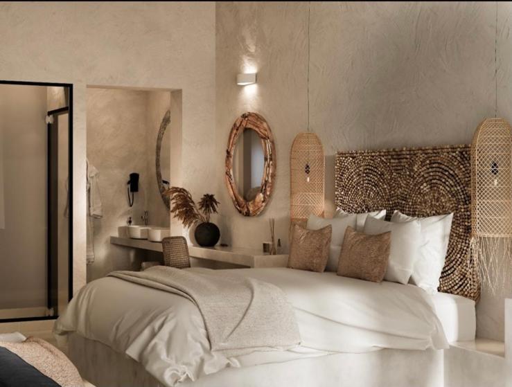 a bedroom with a large white bed and a mirror at Delfini Beach Hotel & Suites in Archangelos