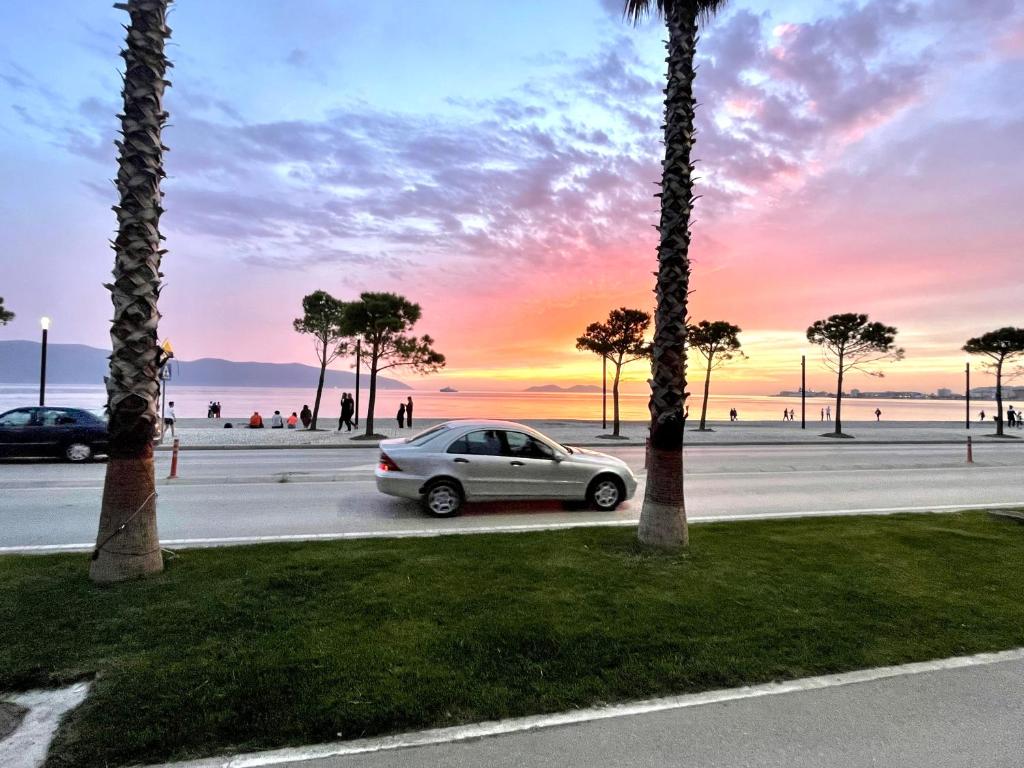 a car parked in a parking lot with palm trees at ELMAR HOTEL in Vlorë