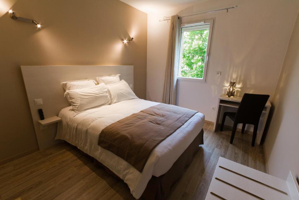 a bedroom with a bed and a desk and a window at Hôtel Les Petits Oreillers in Saint-Martin-dʼArdèche