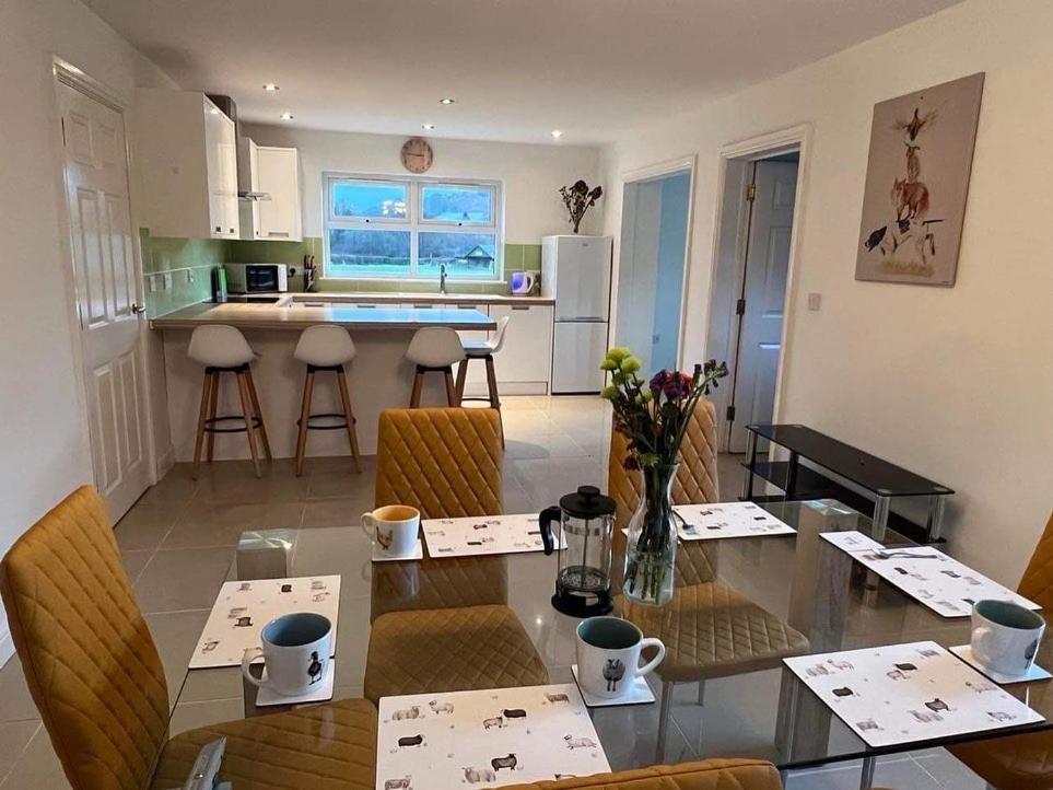 a dining room and kitchen with a table and chairs at Swn yr Coed in Brecon