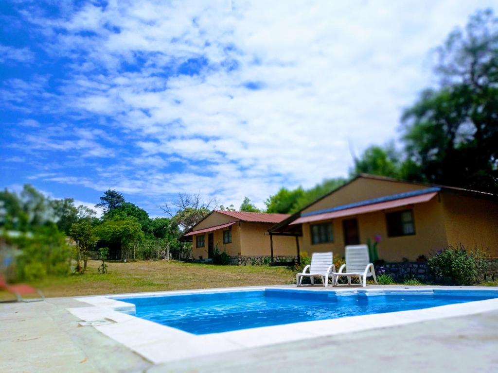 ein Haus mit einem Pool und zwei Stühlen in der Unterkunft Allegra casas de campo in Vaqueros