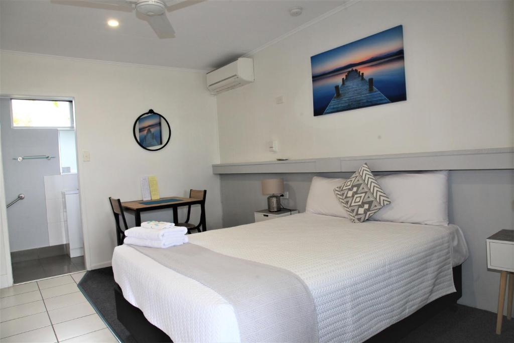 um quarto com uma grande cama branca e uma janela em Charm City Motel em Bundaberg