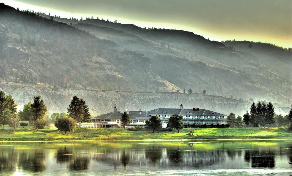 a house next to a lake with a mountain at South Thompson Inn & Conference Centre in Kamloops