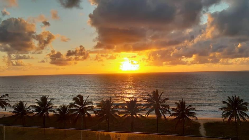 a sunset over the ocean with palm trees on a beach at Apto climatizado à beira-mar c/ piscina-Intermares in Cabedelo