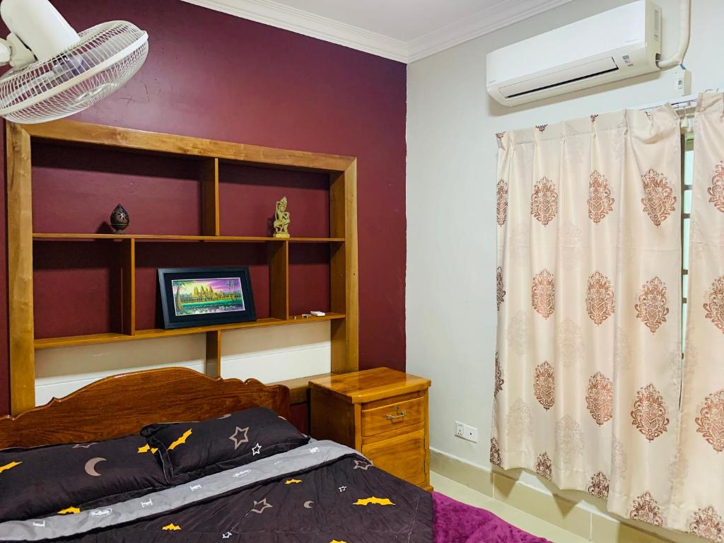 1 dormitorio con 1 cama y TV en la pared en Sweet Home, en Phnom Penh