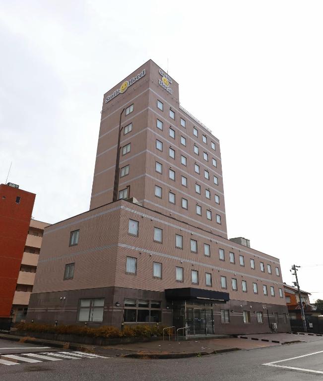 un edificio alto marrón sentado al lado de una calle en Smile Hotel Takaoka Ekimae, en Takaoka