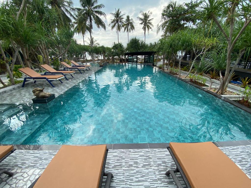 a large swimming pool with chairs and palm trees at The Wynn Kohjum in Ko Jum