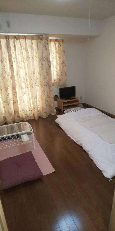 1 dormitorio con 1 cama blanca y TV en ホテルサンクリスター 201, en Tokio