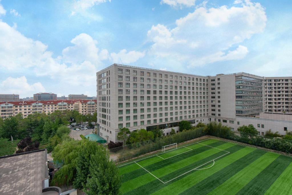 a large building with a soccer field in front of it at Qingdao Parkview Holiday Hotel in Qingdao