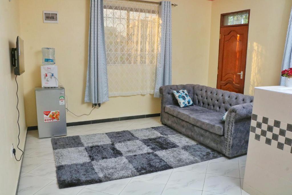 een woonkamer met een bank en een koelkast bij Nice Spacious 1bedroom hideout in bamburi in Mombasa