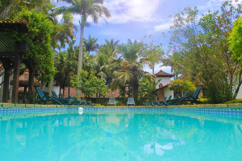 uma grande piscina com cadeiras e palmeiras em OYO Pousada do Wagner, Rio das Ostras em Rio das Ostras