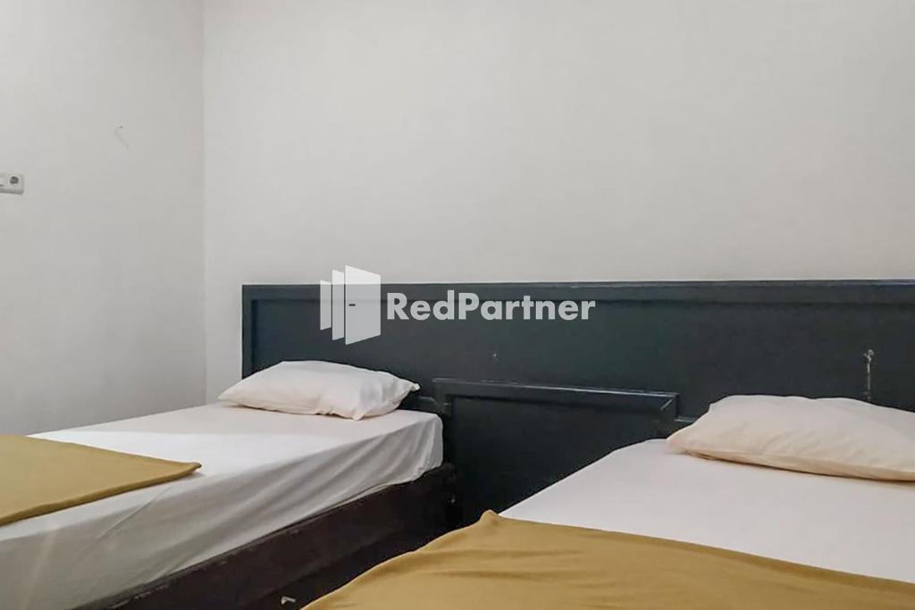 2 posti letto in una camera con un cartello rosso partner di Palu City Guest House Mitra RedDoorz a Palu