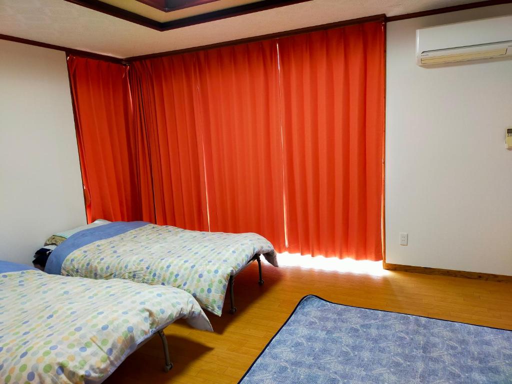 a bedroom with two beds and an orange curtain at Shirahono Yado Aoi Umi in Ishigaki Island