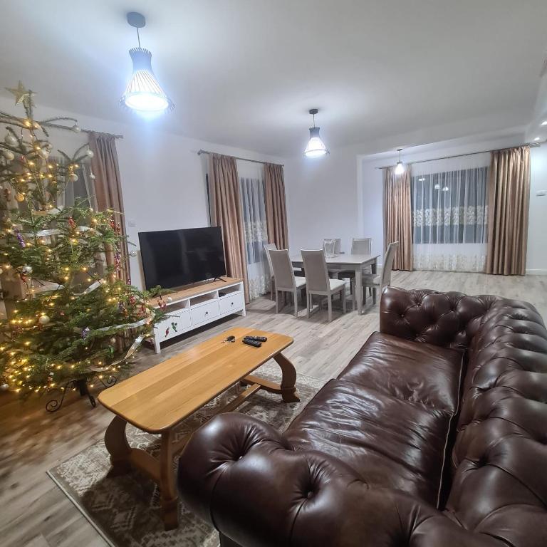 a living room with a leather couch and a christmas tree at Casa Ardeluta in Ardeluţa