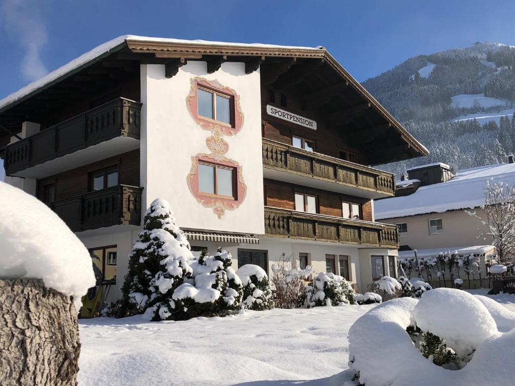 un gran edificio en la nieve con árboles nevados en Sportpension Therese en Westendorf