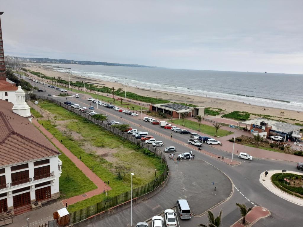 a street with cars parked next to a beach at Tenbury Beach Apartment in Durban