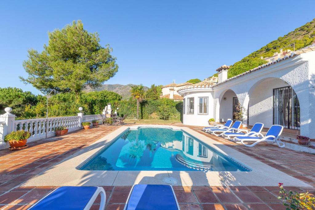 a swimming pool with chairs and a house at Casa Pepe in Mijas