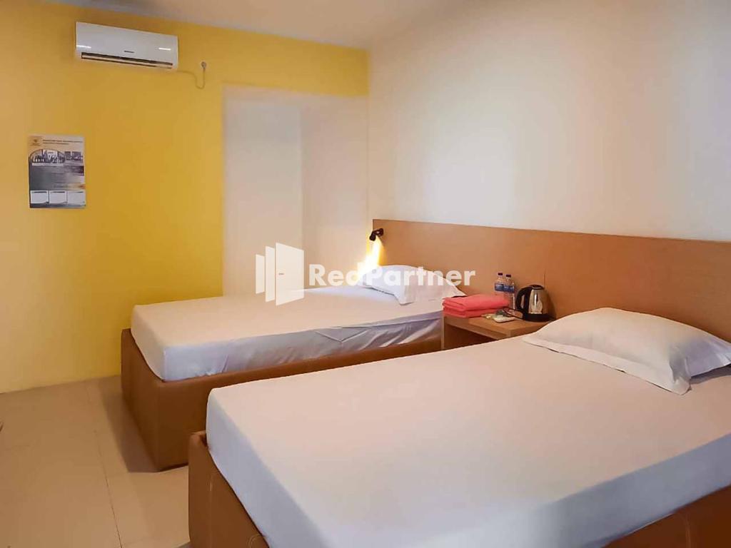 ein Hotelzimmer mit 2 Betten und einem Telefon in der Unterkunft Wisma Baznas Syariah Majalengka Mitra RedDoorz in Majalengka