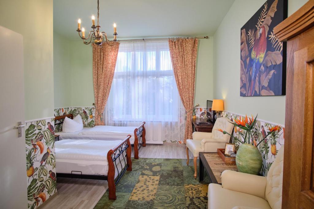 a bedroom with two beds and a living room at Anno 1900 Hotel Babelsberg in Potsdam