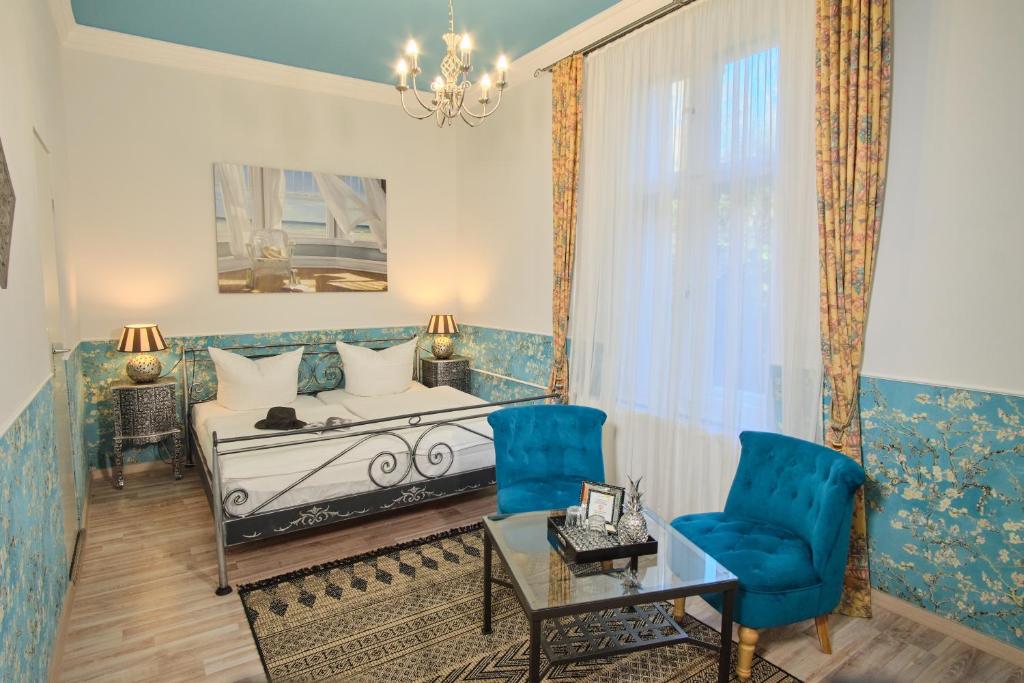 a bedroom with a bed and two blue chairs at Anno 1900 Hotel Babelsberg in Potsdam