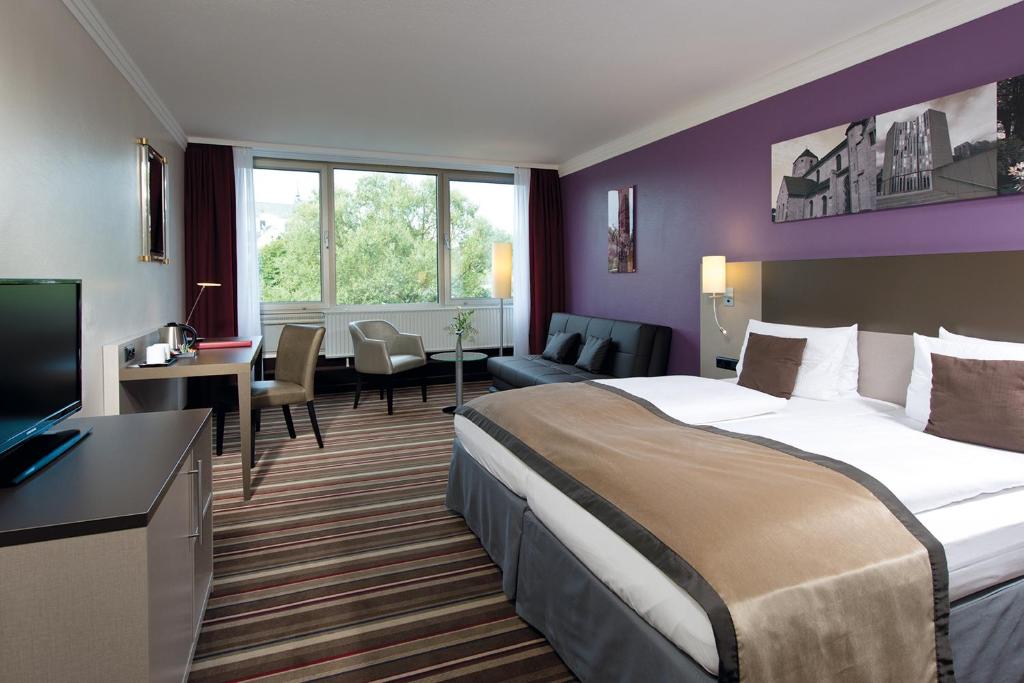 ein Hotelzimmer mit einem großen Bett und einem Wohnzimmer in der Unterkunft Leonardo Hotel Mönchengladbach in Mönchengladbach