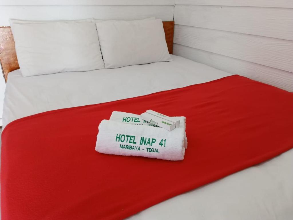 a bed with a red blanket and a book on it at Hotel 41 Maribaya in Tegal