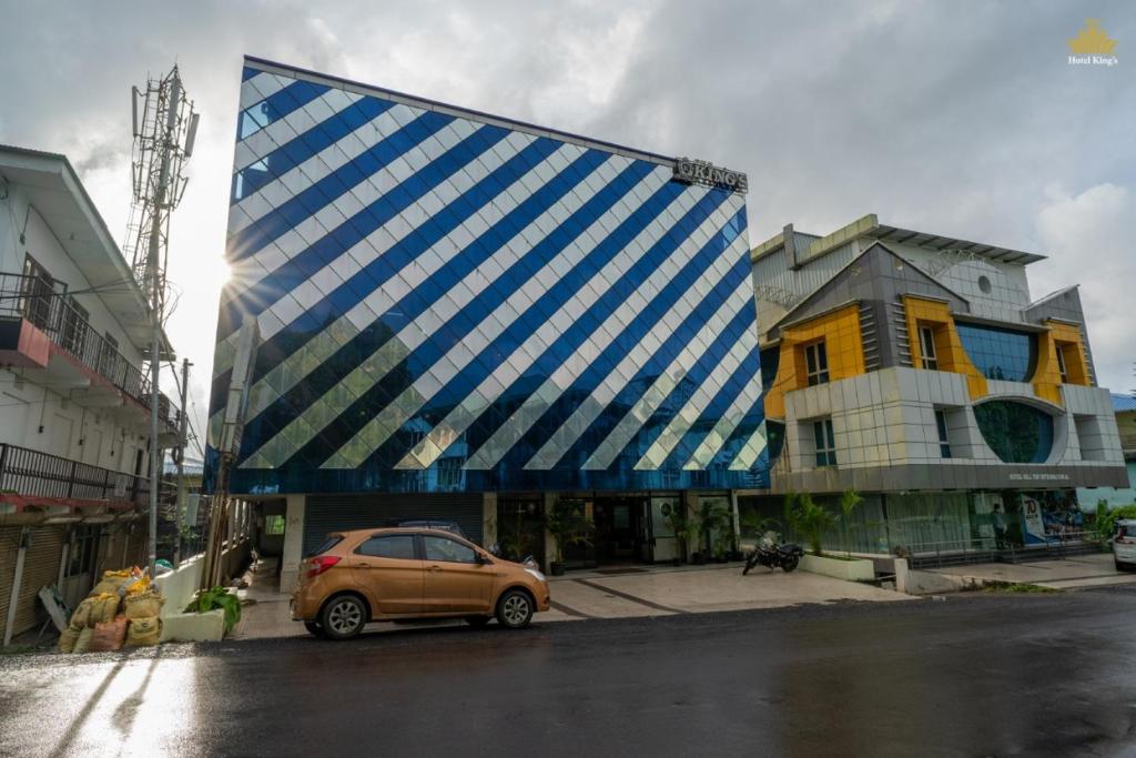 Un edificio azul y blanco con un coche aparcado delante. en Hotel The King's, en Port Blair