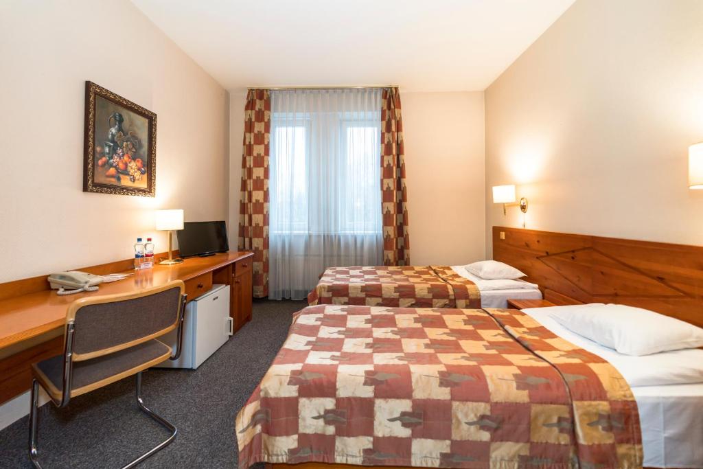 a hotel room with two beds and a desk at Kolonna Hotel Brigita in Rīga