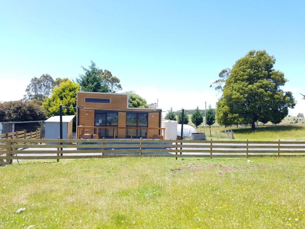 una casa en un campo con una valla en Tiny Cradle at The Good Place, en Staverton