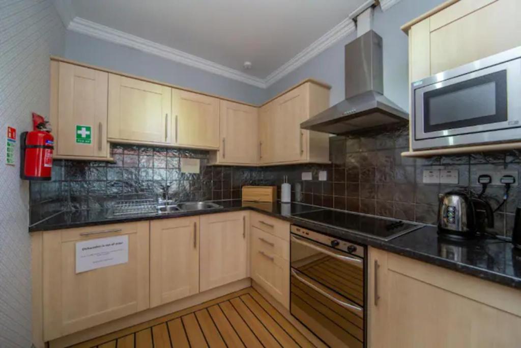 uma cozinha com armários de madeira e um forno com placa de fogão em Tron Kirk Residence em Edinburgo