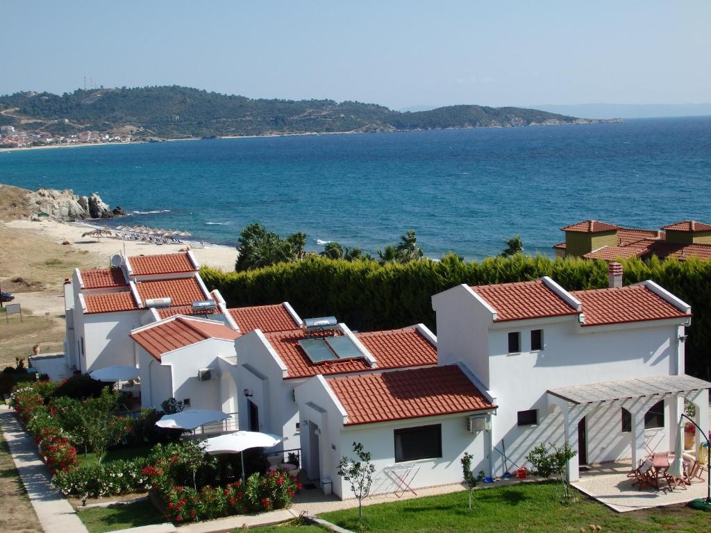 una fila de casas blancas junto al océano en Ktima Amitsa Studios & Apartments, en Sarti