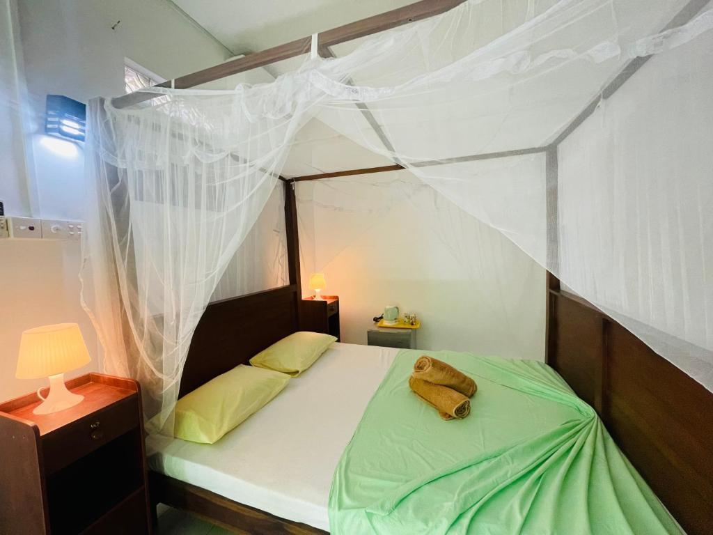 a bedroom with a canopy bed with a stuffed animal on it at Bougain Villa Sea View in Mirissa