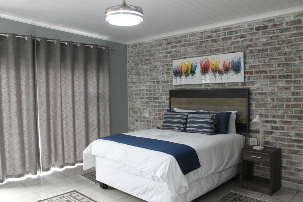 a bedroom with a bed and a brick wall at Berry Lane Guesthouse in Kroonstad