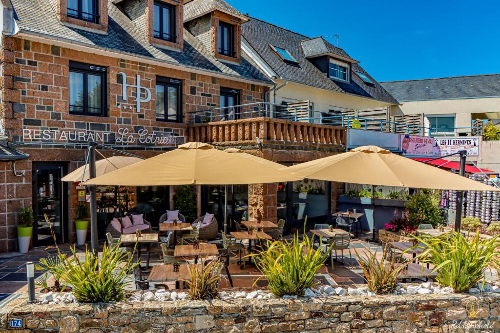 een restaurant met tafels en parasols voor een gebouw bij Logis Hôtel du Parc in Perros-Guirec