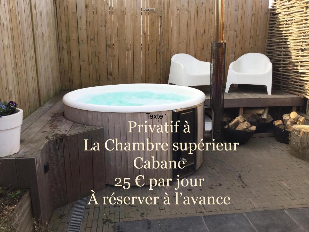 uma banheira de hidromassagem num quintal com duas cadeiras brancas em B&B L'Eau Claire em La Hulpe