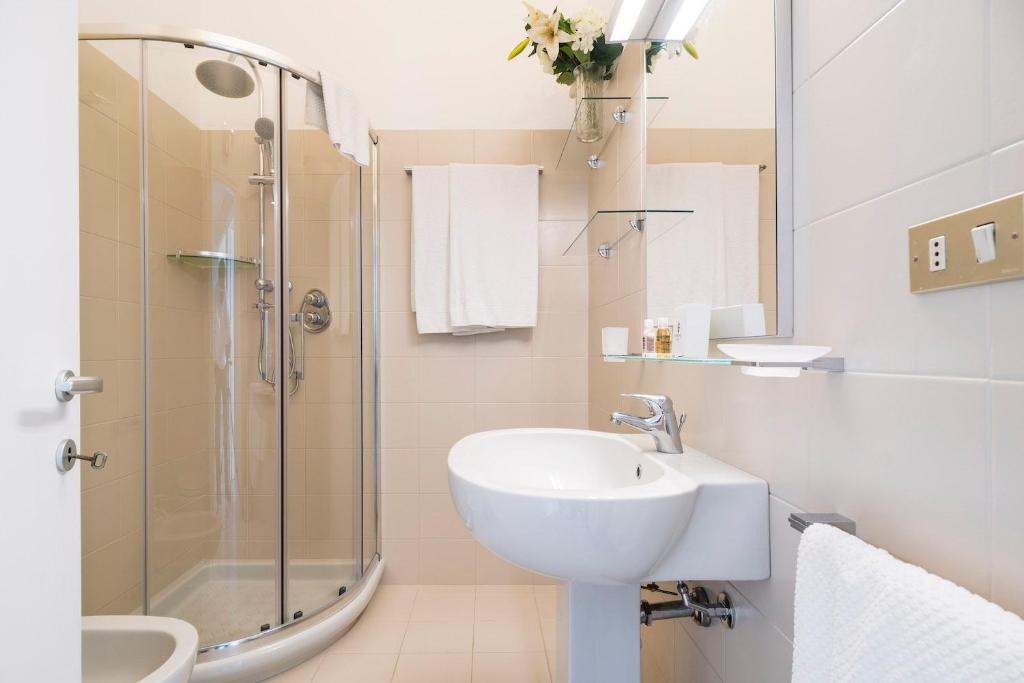 biała łazienka z umywalką i prysznicem w obiekcie Contempora Apartments - Elvezia 8 - E52 w Mediolanie