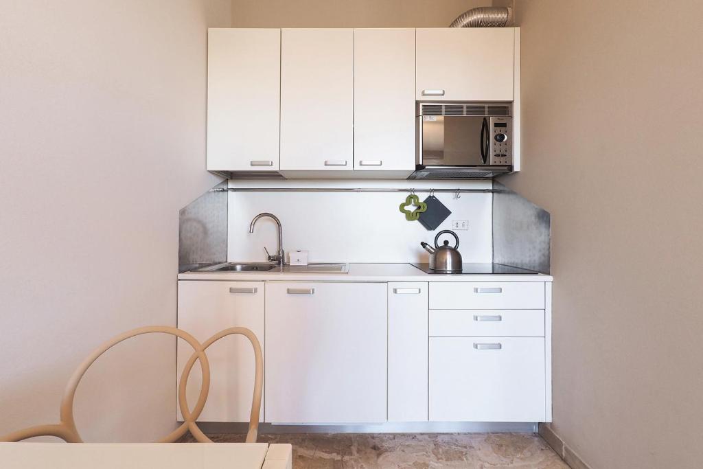 Biała kuchnia ze zlewem i kuchenką mikrofalową w obiekcie Contempora Apartments - Elvezia 8 - E52 w Mediolanie