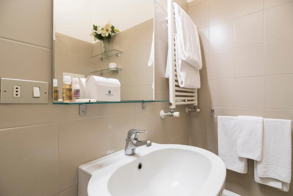 W łazience znajduje się umywalka, lustro i ręczniki. w obiekcie Contempora Apartments - Elvezia 8 - E54 w Mediolanie