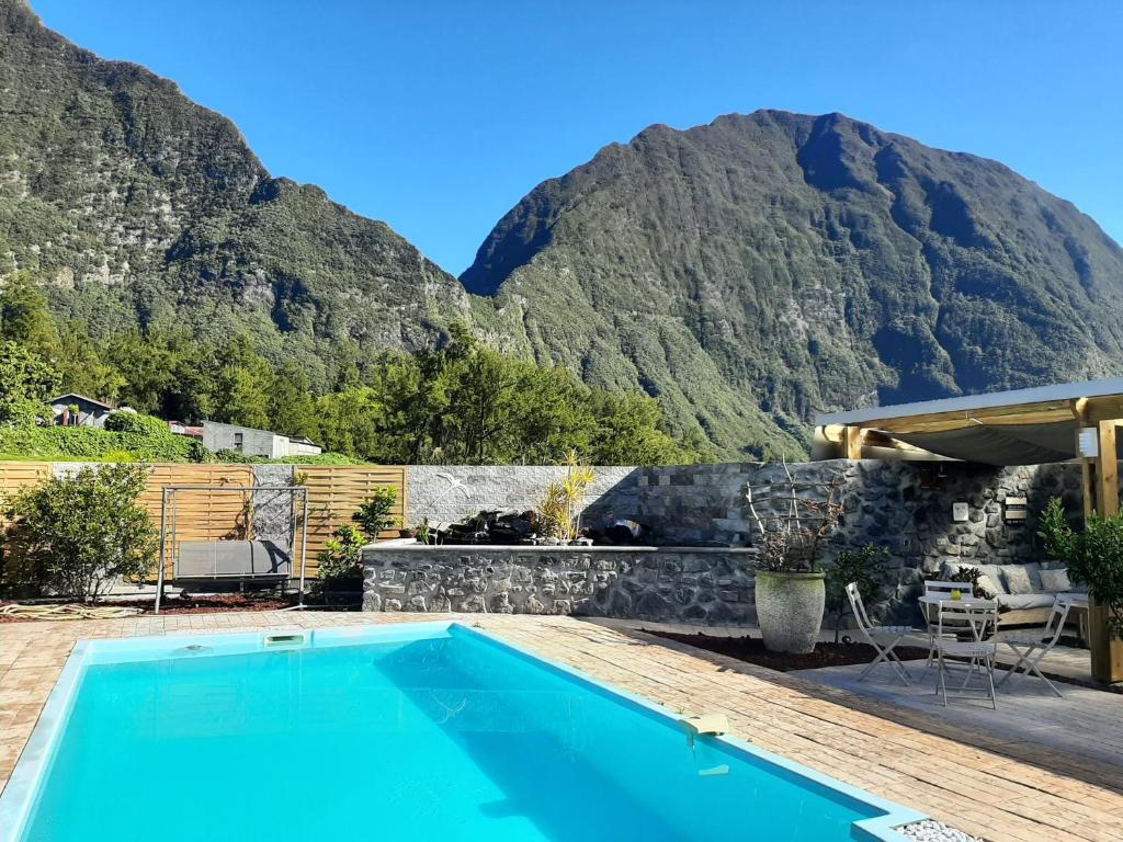 a swimming pool with a mountain in the background at La Croisee des Sentiers in Salazie