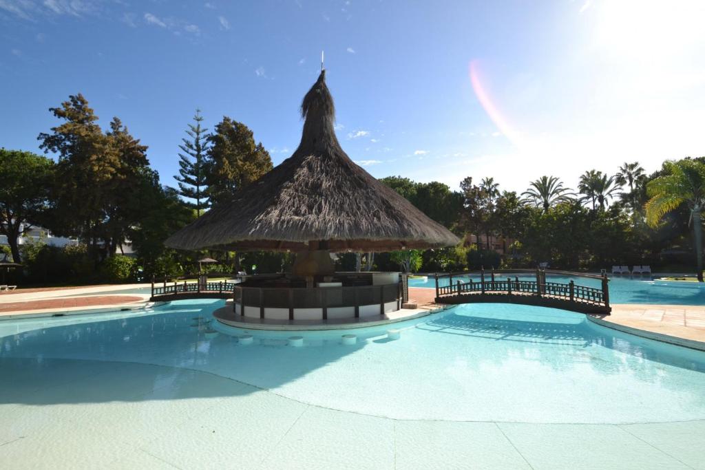 duży basen ze słomianym parasolem w środku w obiekcie Beautiful, Bright and Spacious Duplex in Marbella w mieście Estepona