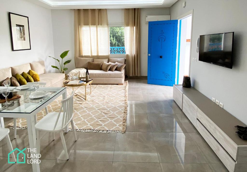 a living room with a table and a blue door at Le Safran - apt renove, spacieux et central a Marsa in Carthage