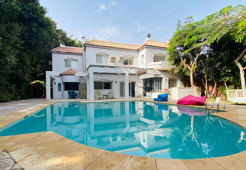 a large swimming pool in front of a house at Villa by the Pyramids in Cairo